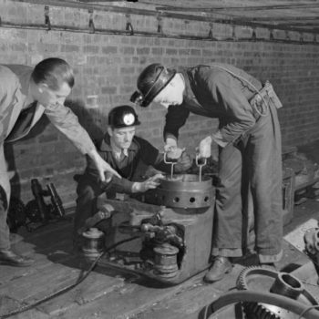 Classic British workwear clothing,1944 photo of Men in work clothing at the British Training School Sheffield, West Riding, Yorkshire, England, UK, using American Mining Equipment,