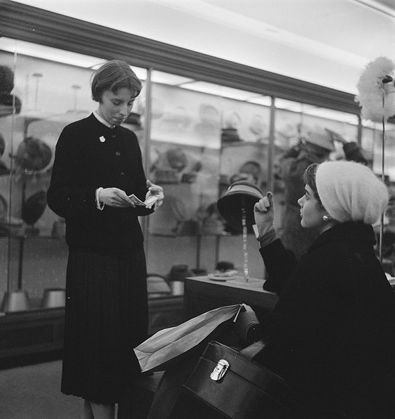 Woman shopping for hats in millinary department, 1957