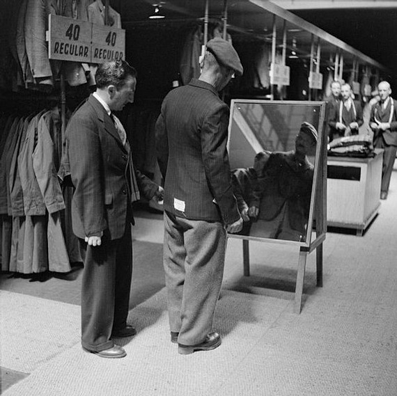 Private Bill Krepper, Pioneer Corps tries his demob suit in front of a standing morror with a civilian tailor at the demobilisation clothing depot, Olympia, London, photo shot estimated timedate between 1939 and 1945