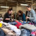 What cleaning processes do thrift stores use on donated clothes - Thrift store staff members sorting through piles of donated clothes, inspecting each item for quality and wearability.