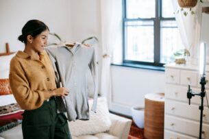 Second Hand Clothes Trends - A young influencer creating a TikTok video showcasing vintage fashion finds in a trendy bedroom setting