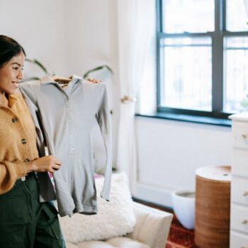 Second Hand Clothes Trends - A young influencer creating a TikTok video showcasing vintage fashion finds in a trendy bedroom setting